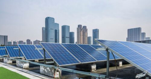 A cityscape backdrop behind rows of rooftop solar panels