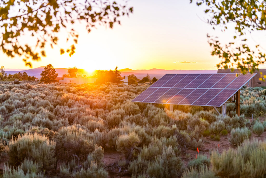 Ranchos de Taos valley green landscape in summer and solar panels during sunset with sun rays in New Mexico